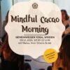 Eine Gruppe von Menschen sitzt im Kreis. Davor ein Banner mit den Worten: Mindful Cacao Morning sowie Datum und Uhrzeit des Events